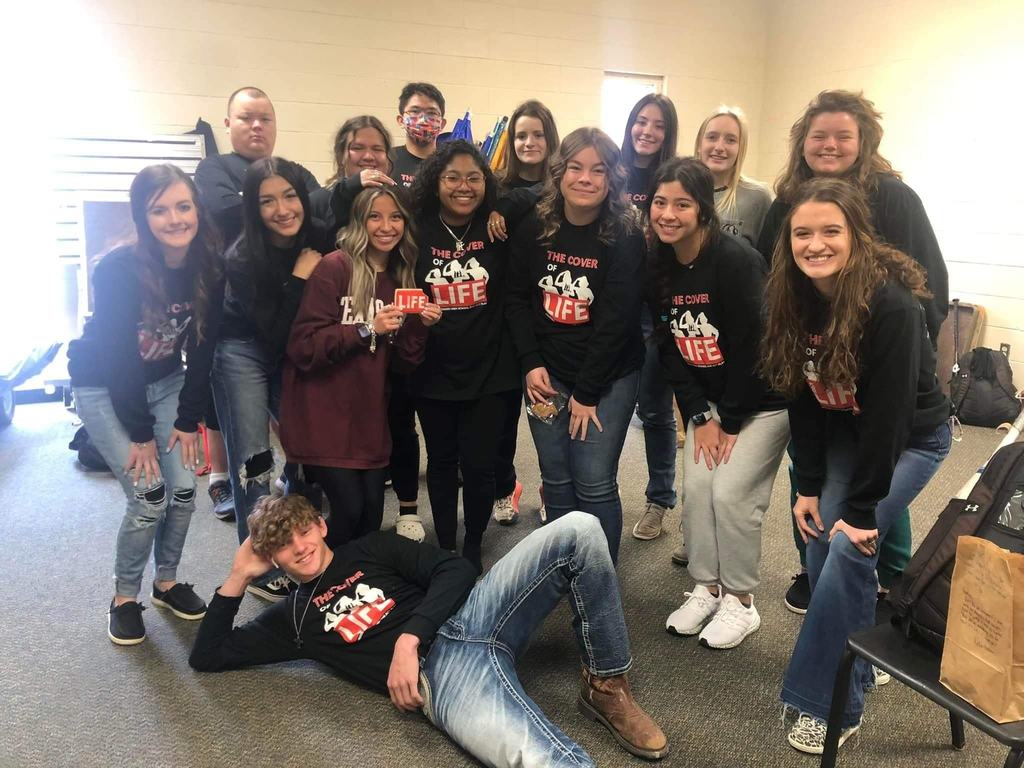 15 high school students posed together in black long sleeve t-shirts 